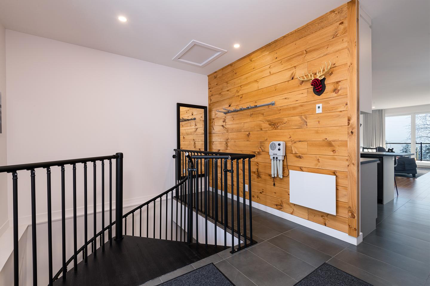 Escalier intérieur avec rampe noire et mur en bois, décor moderne.