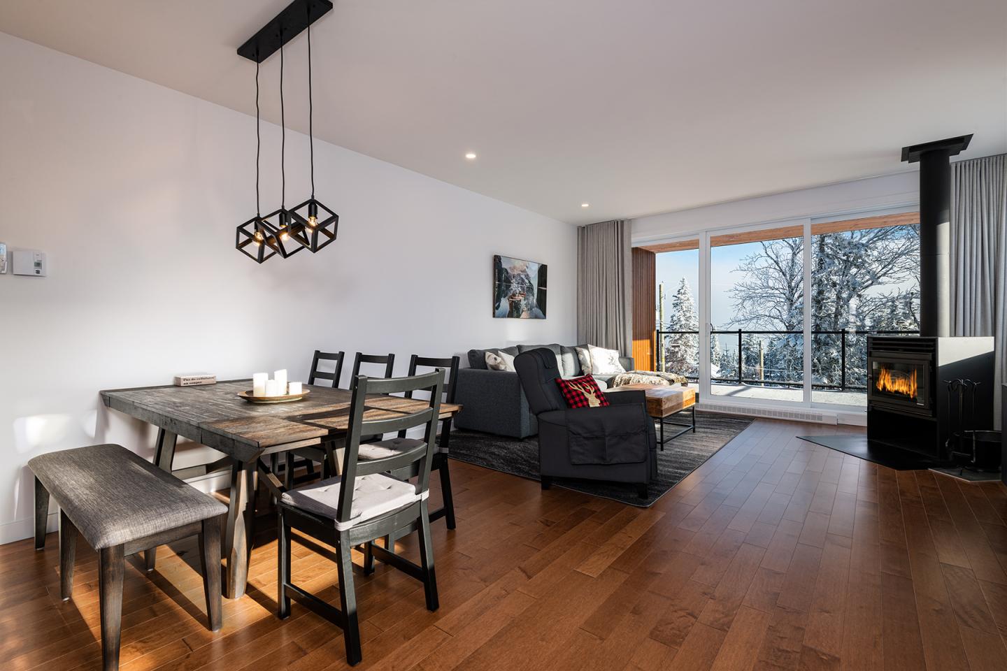 Salle à manger et salon modernes avec vue sur la neige, cheminée allumée.