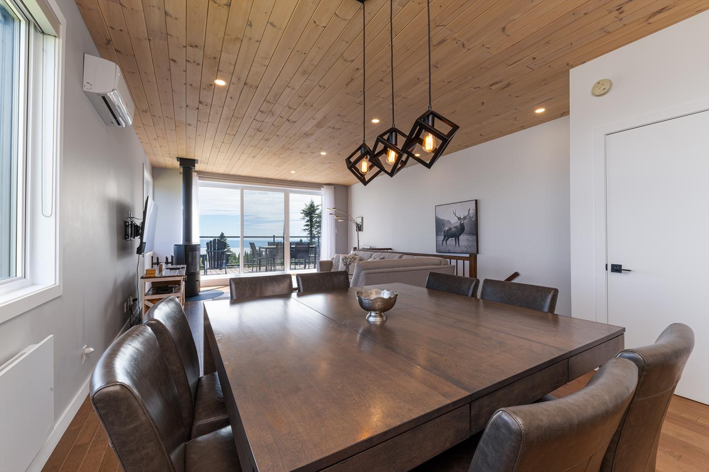 Salle à manger contemporaine avec table en bois, chaises en cuir, et plafond en bois.
