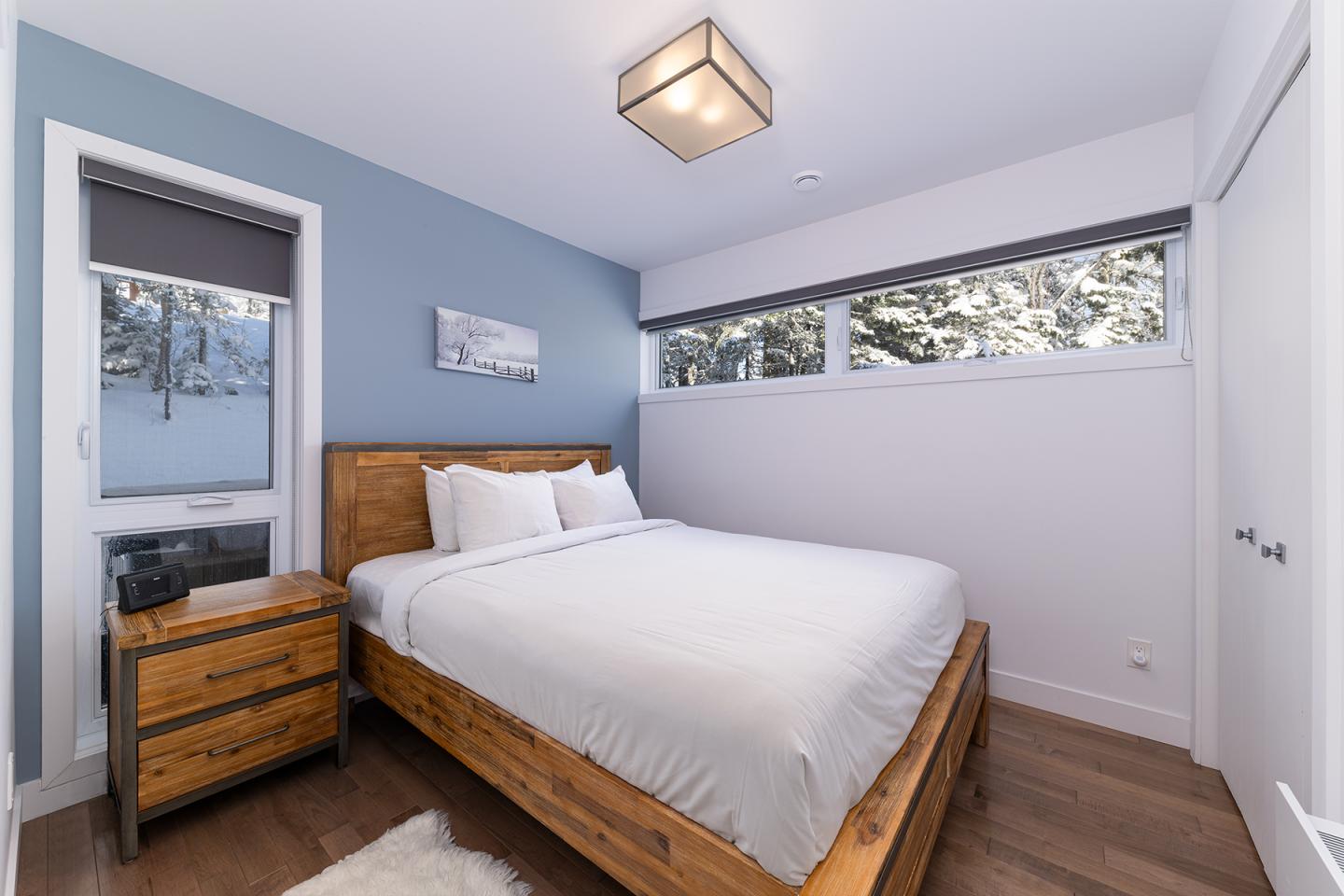 Chambre lumineuse avec murs bleus, lit en bois, et table de chevet.