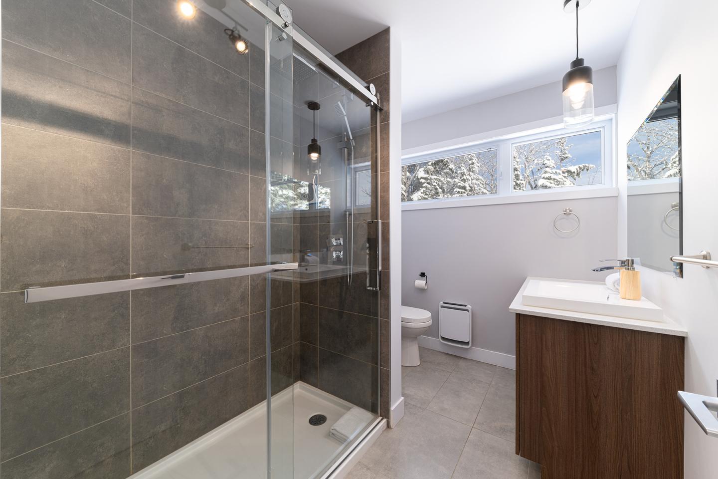 Salle de bain moderne avec douche vitrée et lavabo sur meuble en bois.