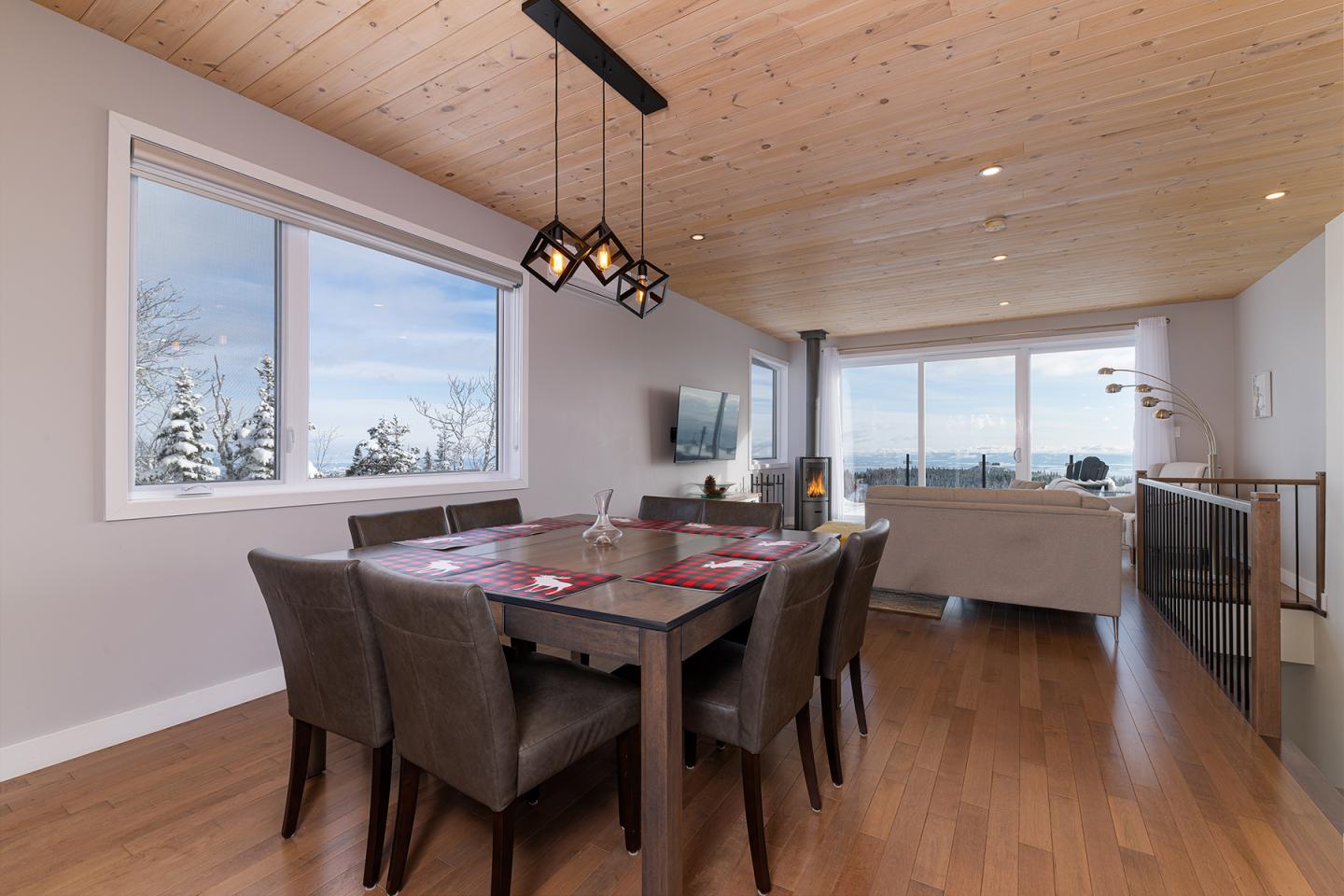 Salle à manger moderne avec table en bois et vue panoramique par la fenêtre.