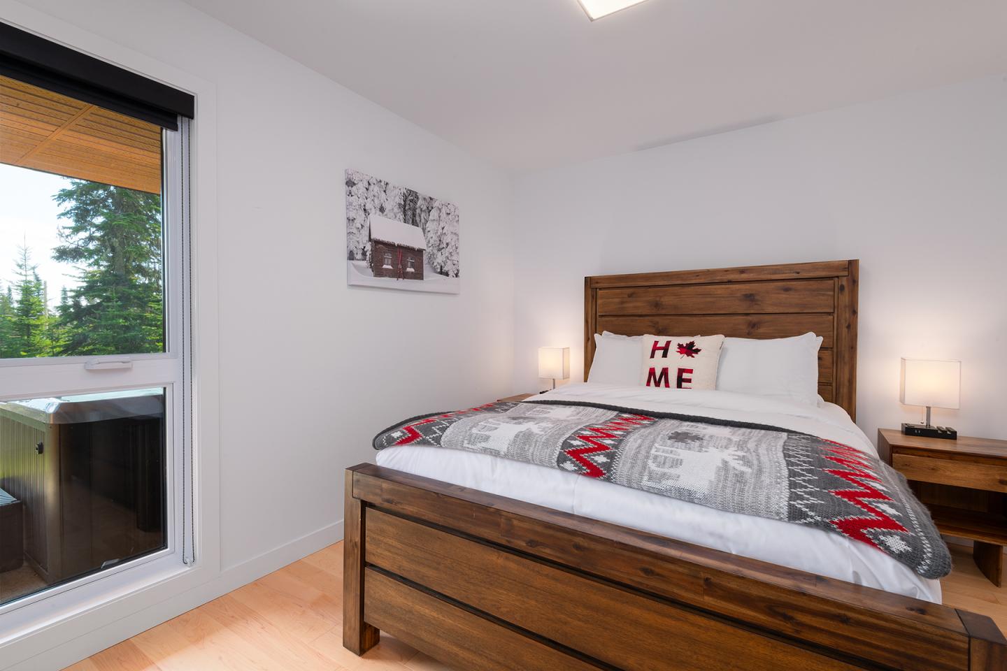 Chambre moderne avec lit en bois, grande fenêtre et décoration murale simple.