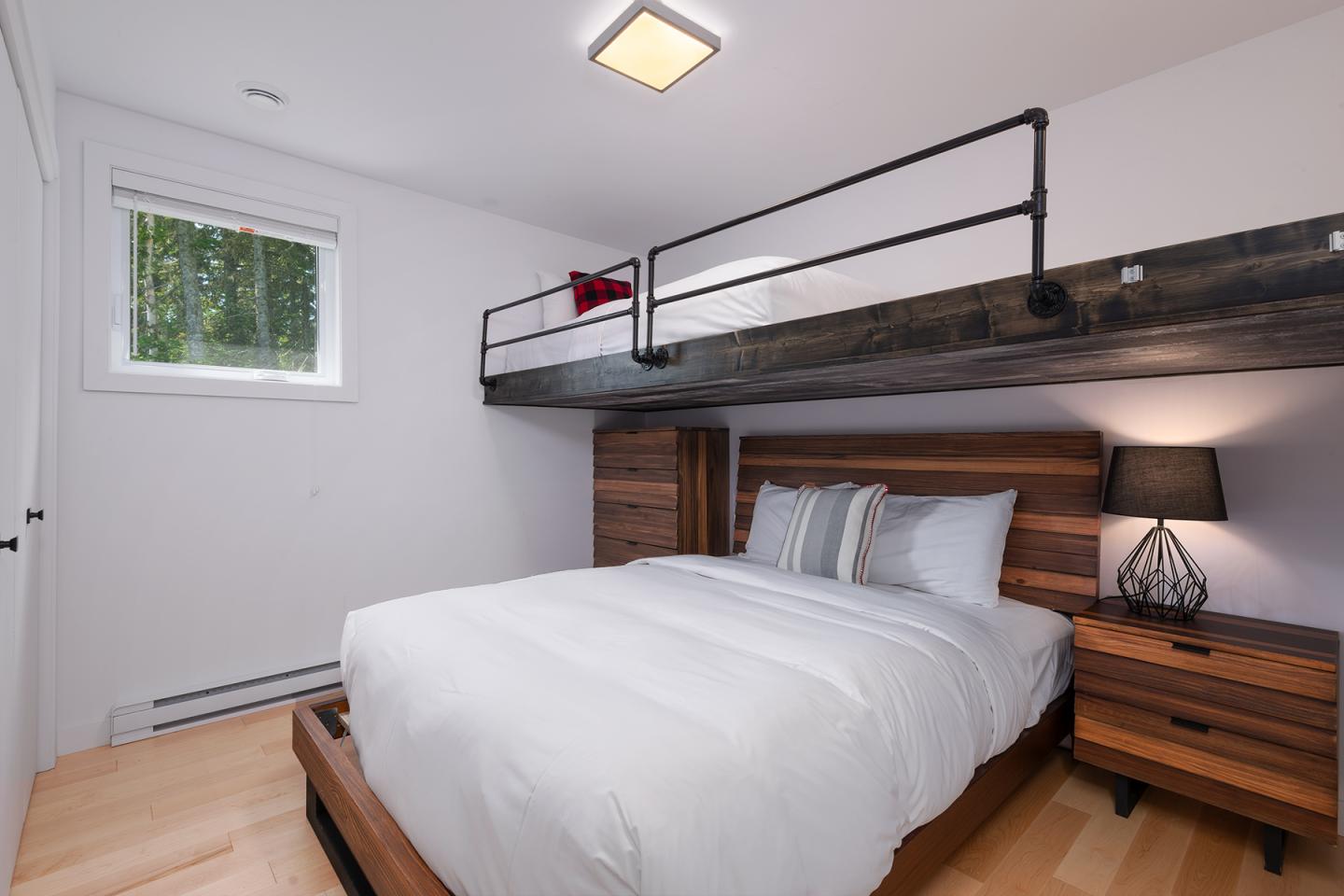 Chambre avec lit double et lit superposé, murs blancs.