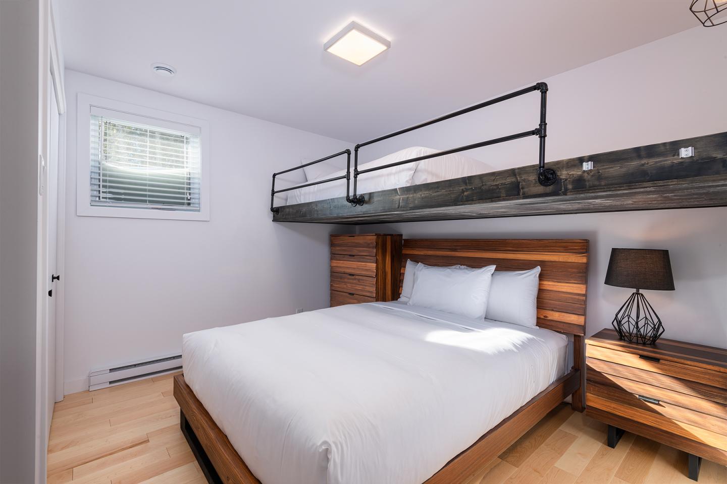 Chambre moderne avec lit double, mezzanine et lumière douce.