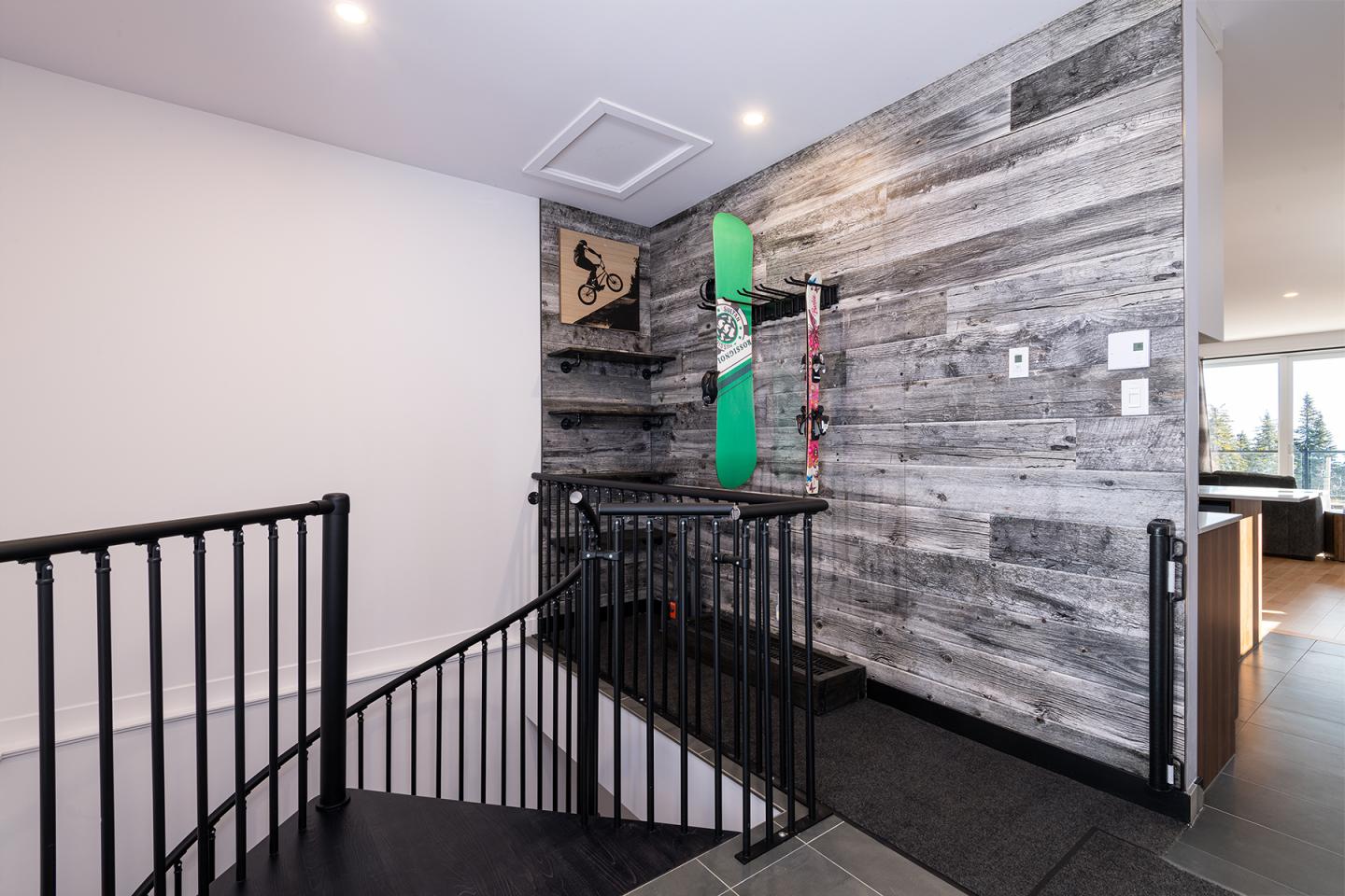 Escalier moderne avec mur en bois, snowboard vert exposé.
