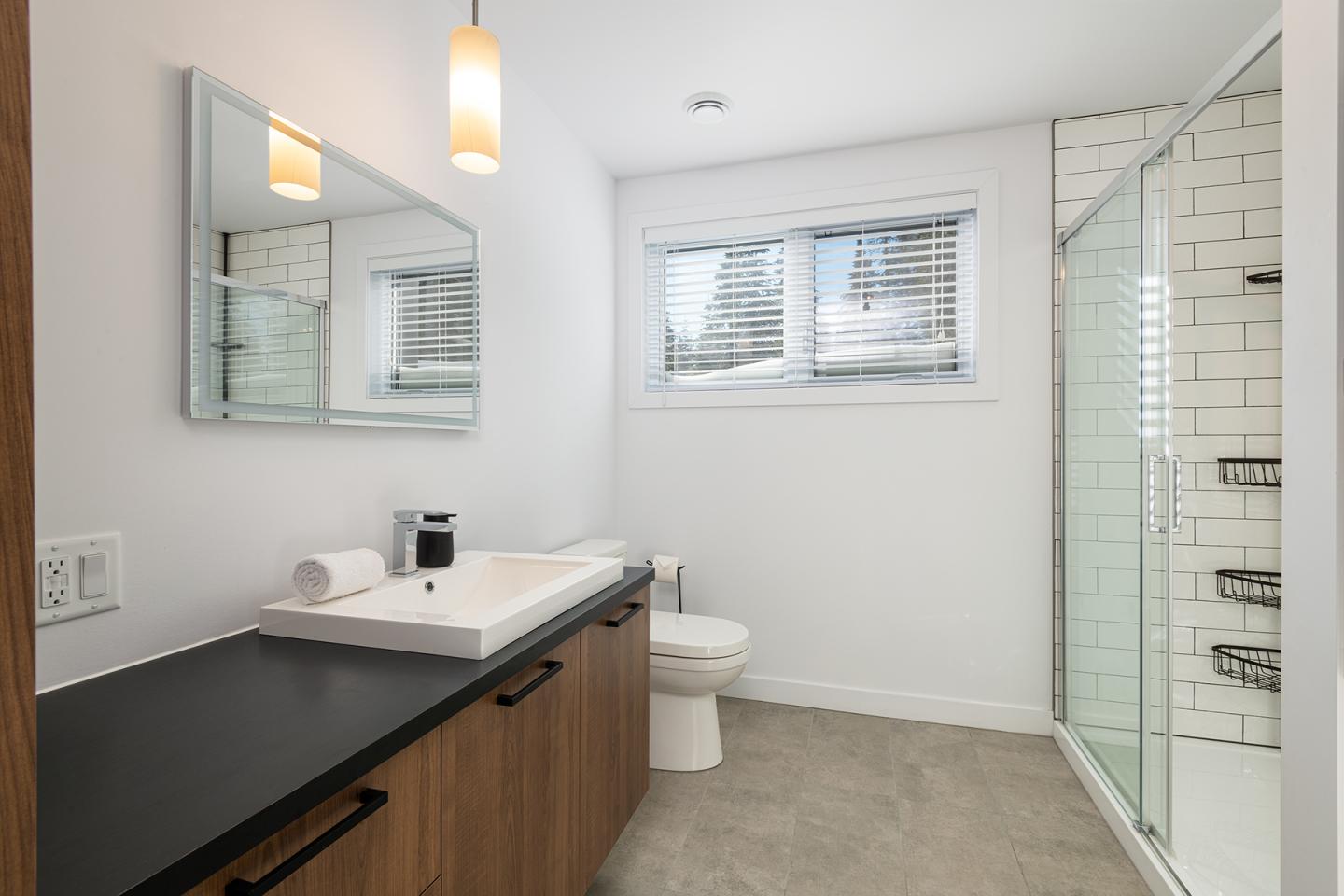 Salle de bain moderne avec lavabo, douche vitrée et mur carrelé.