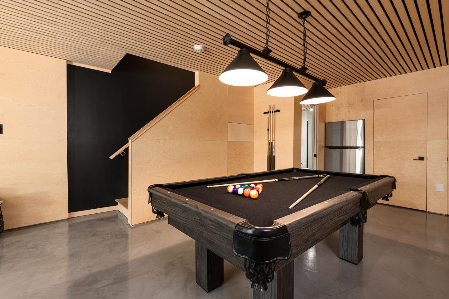 Billard noir dans une pièce moderne avec lumière suspendue.