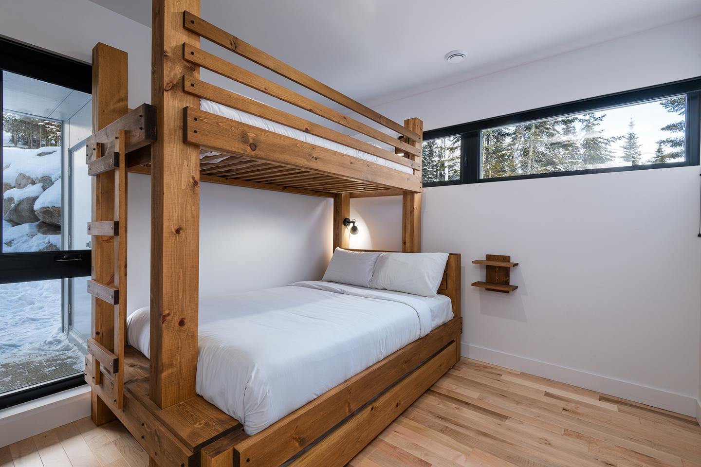 Lit superposé en bois dans une chambre lumineuse avec vue sur la neige.