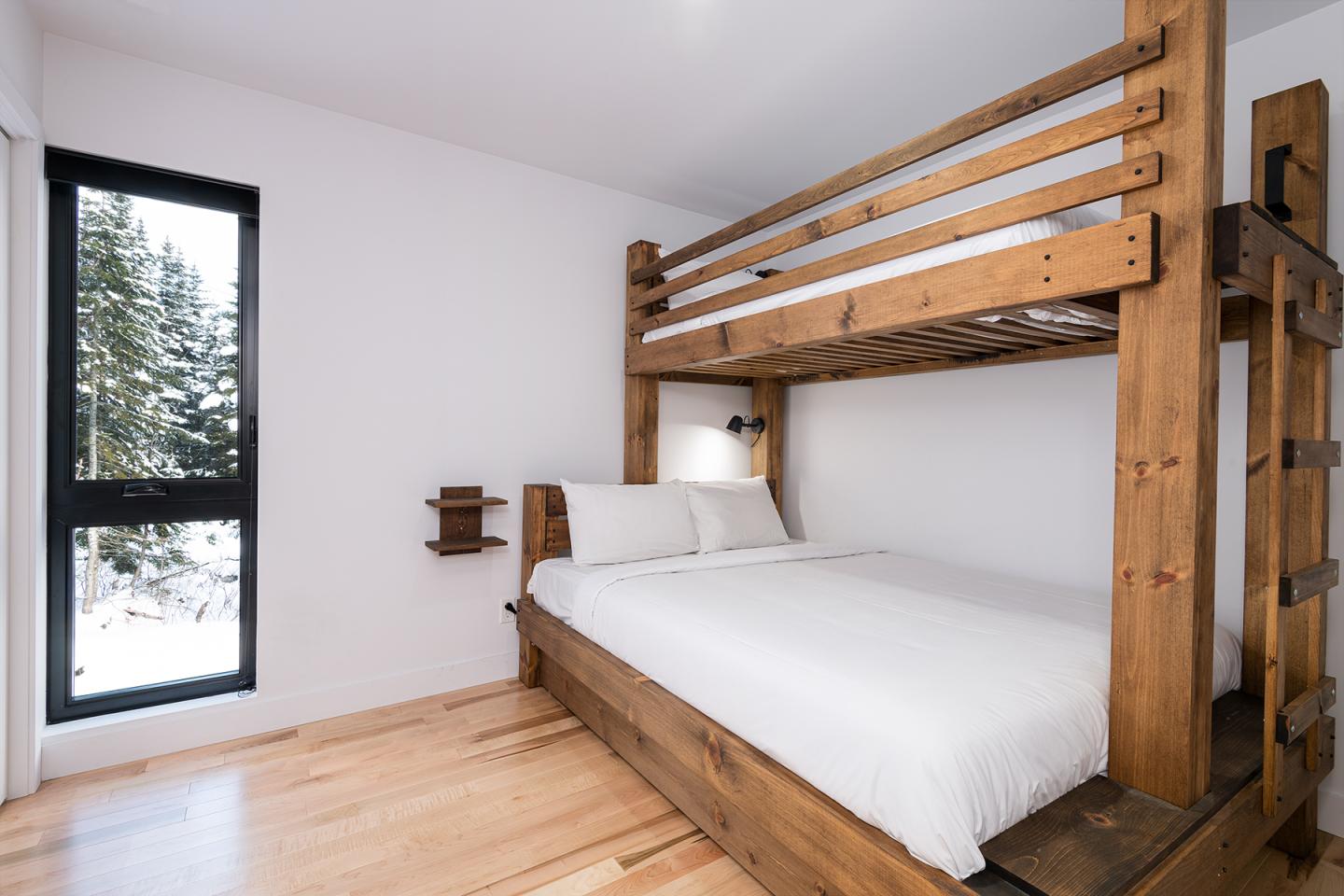 Lit superposé en bois dans une chambre lumineuse avec parquet.