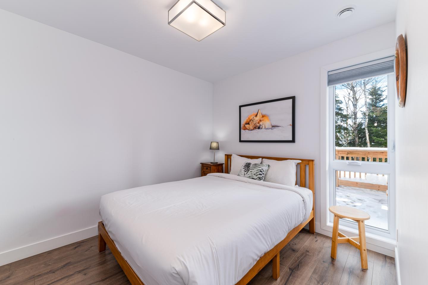 Chambre moderne avec lit double, décor minimaliste et grande fenêtre.
