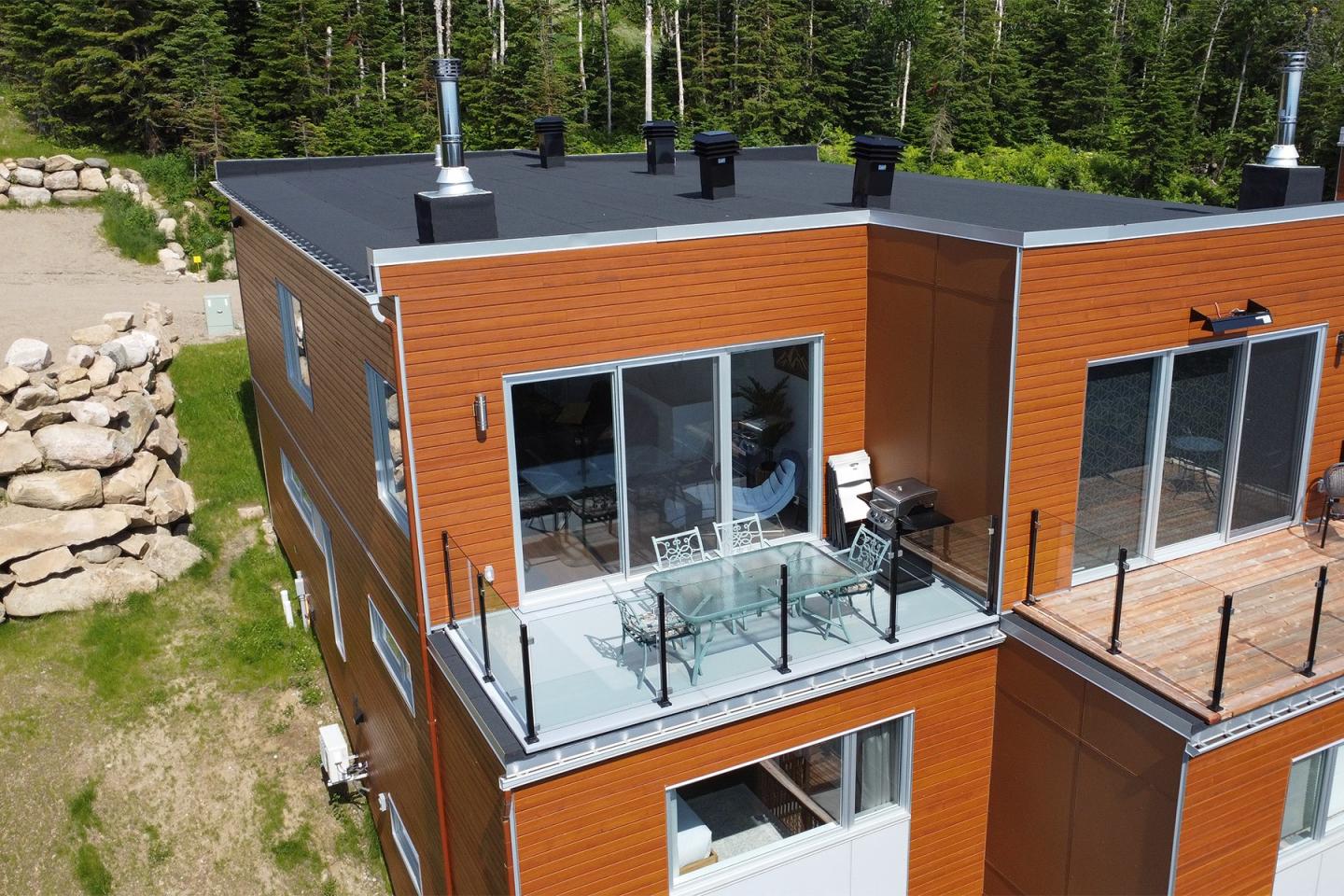 Maison moderne en bois avec balcon et vue sur la forêt.