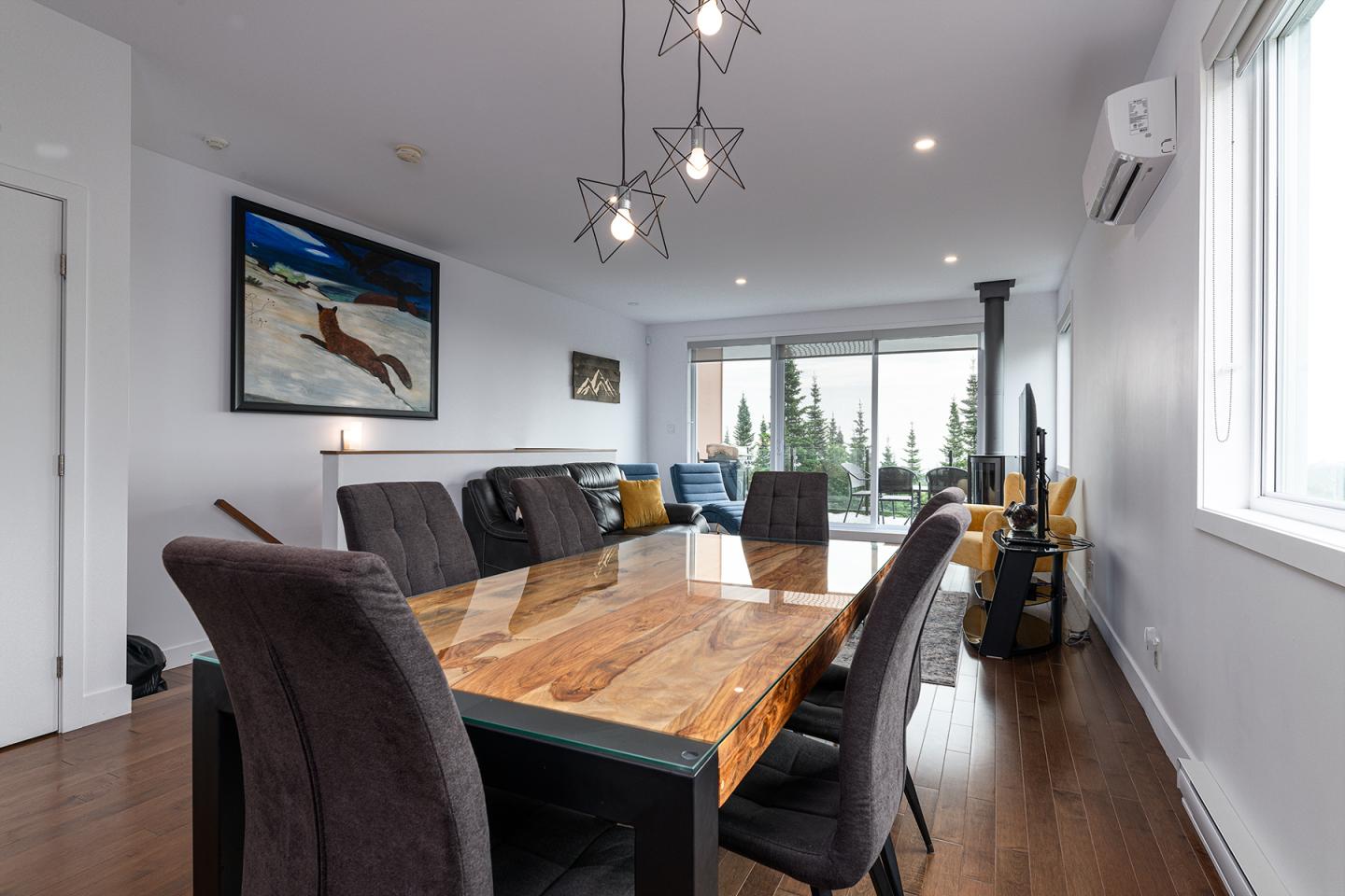 Salle à manger moderne avec table en bois, chaises marron et éclairage pendante.