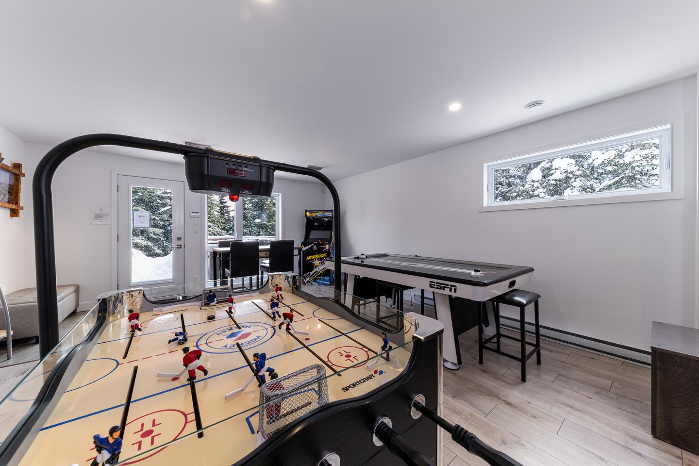 Salle de jeux lumineuse avec table de hockey et baby-foot, sol en bois clair.