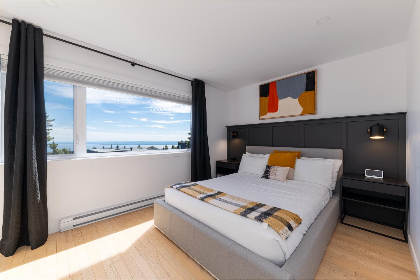 Chambre lumineuse avec vue sur la mer, lit double, décoration moderne.