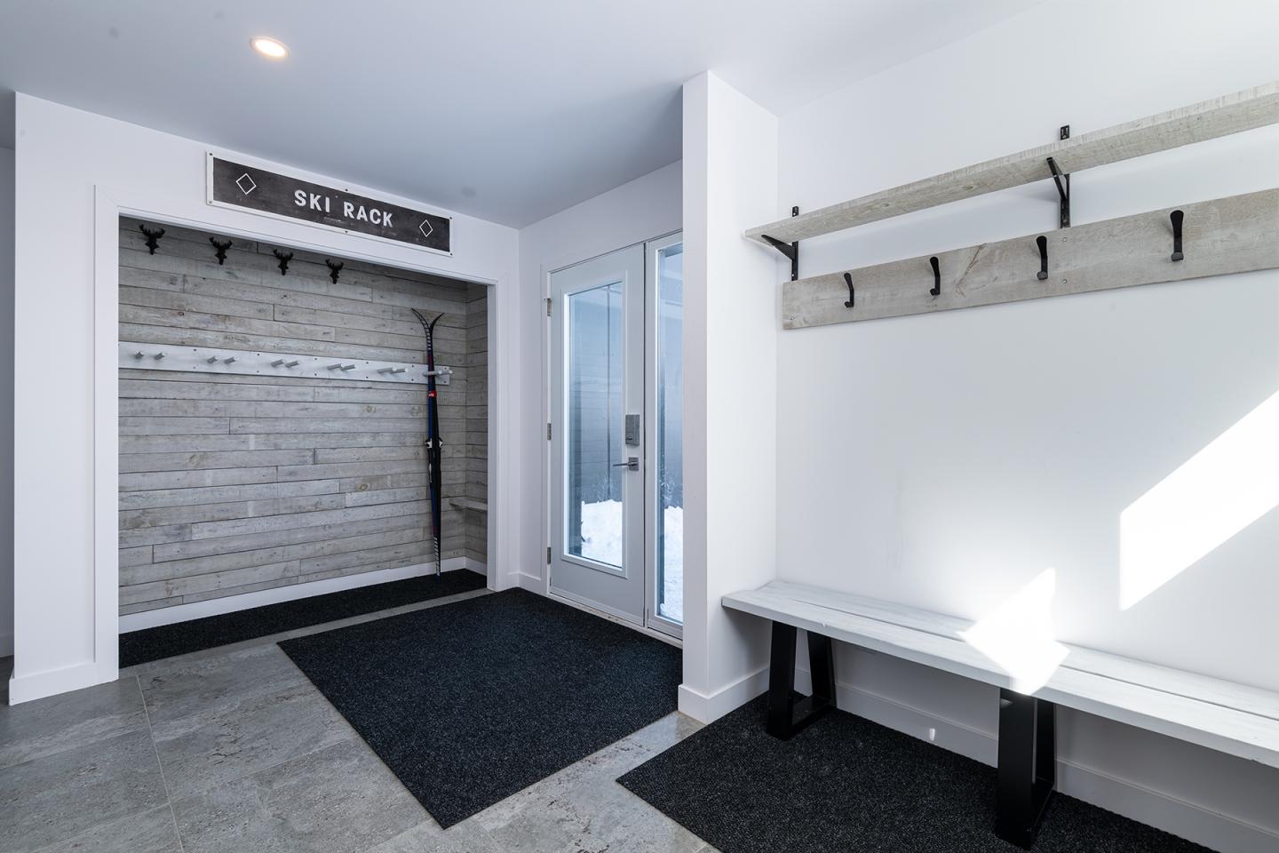 Vestiaire moderne avec banc et crochets sur mur blanc.