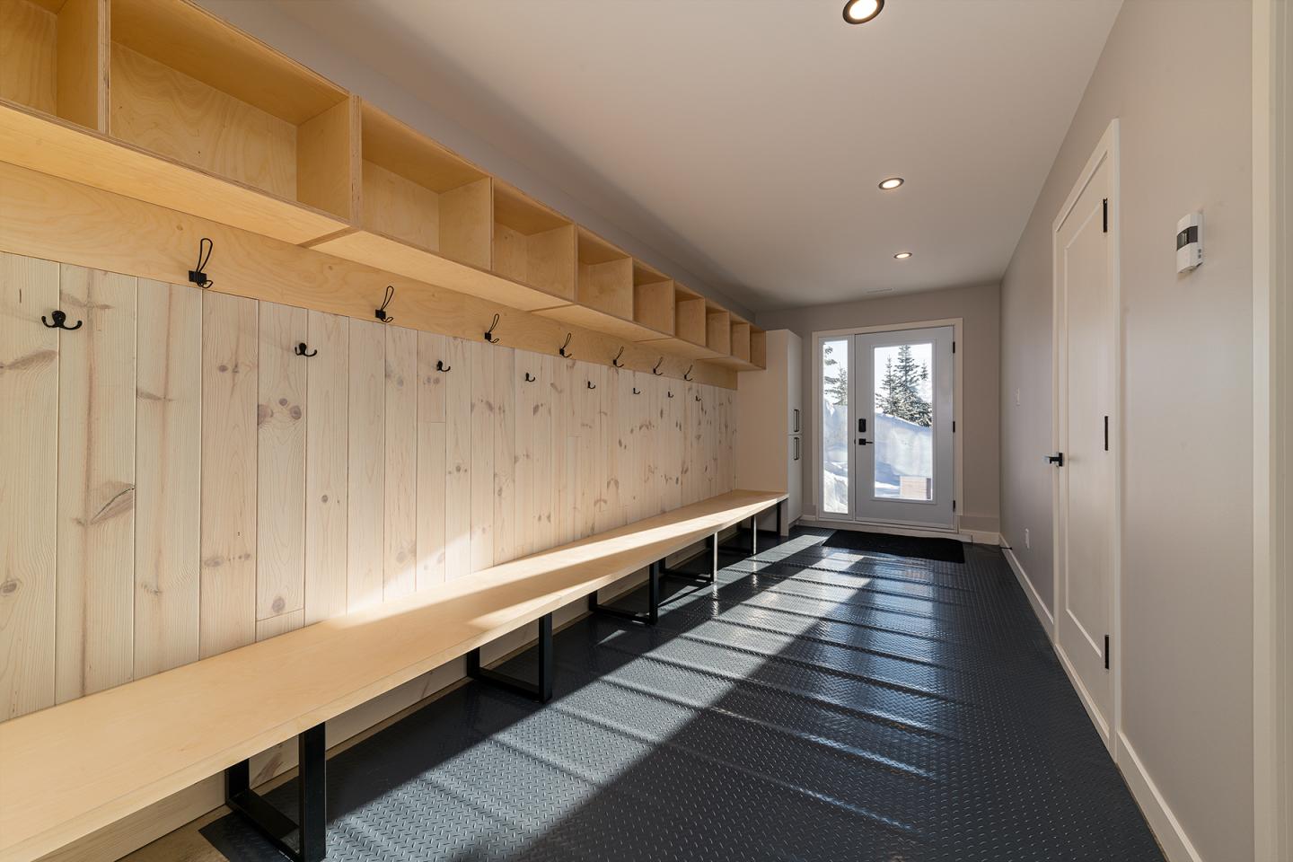 Vestiaire lumineux avec bancs en bois, espace de rangement en hauteur.