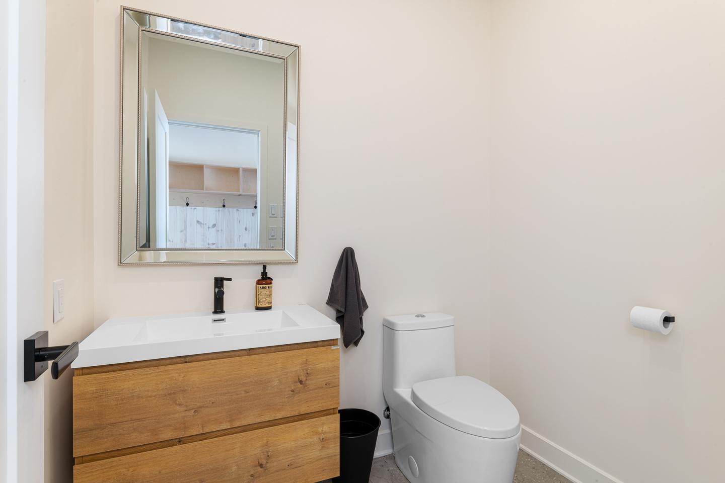 Salle de bain moderne avec lavabo en bois, miroir et toilettes blanches.