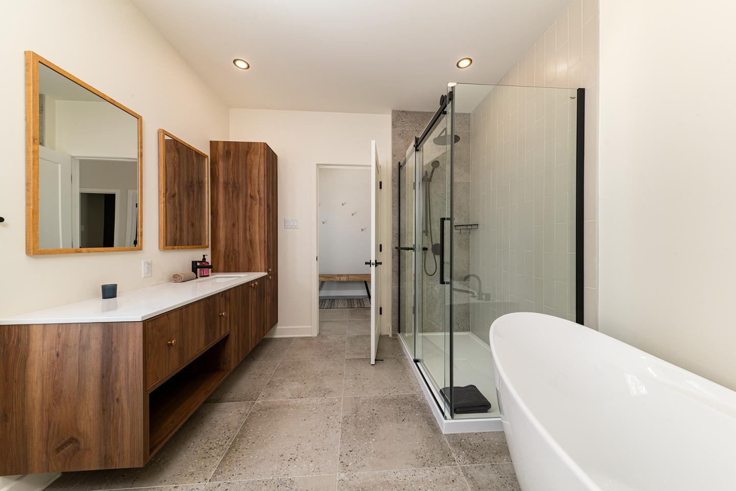 Salle de bain moderne avec baignoire, douche vitrée et meuble en bois.