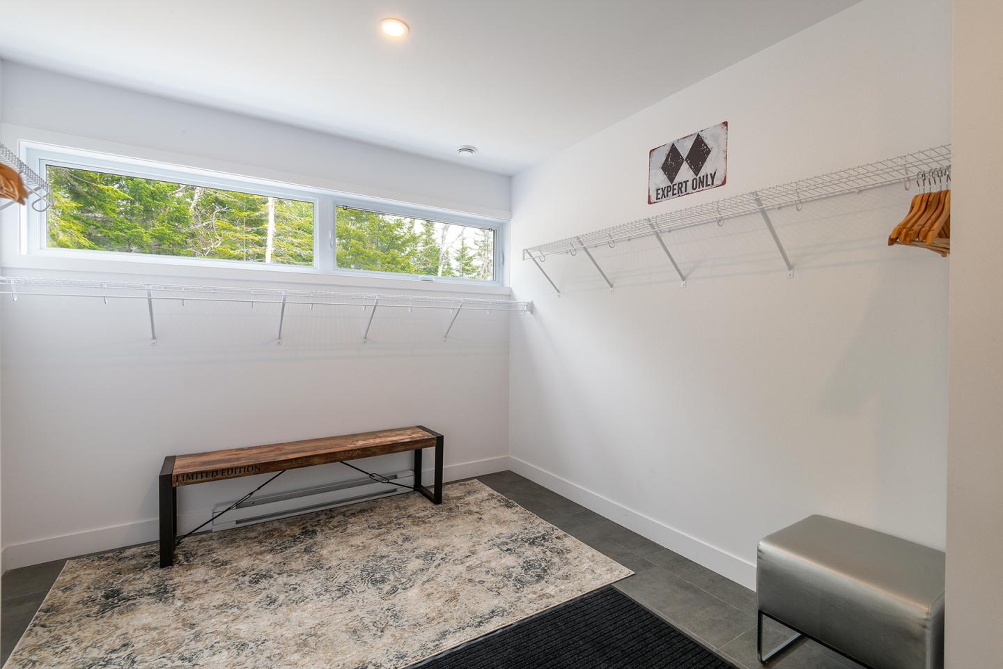 Vestiaire lumineux avec banc en bois, tapis et étagères.