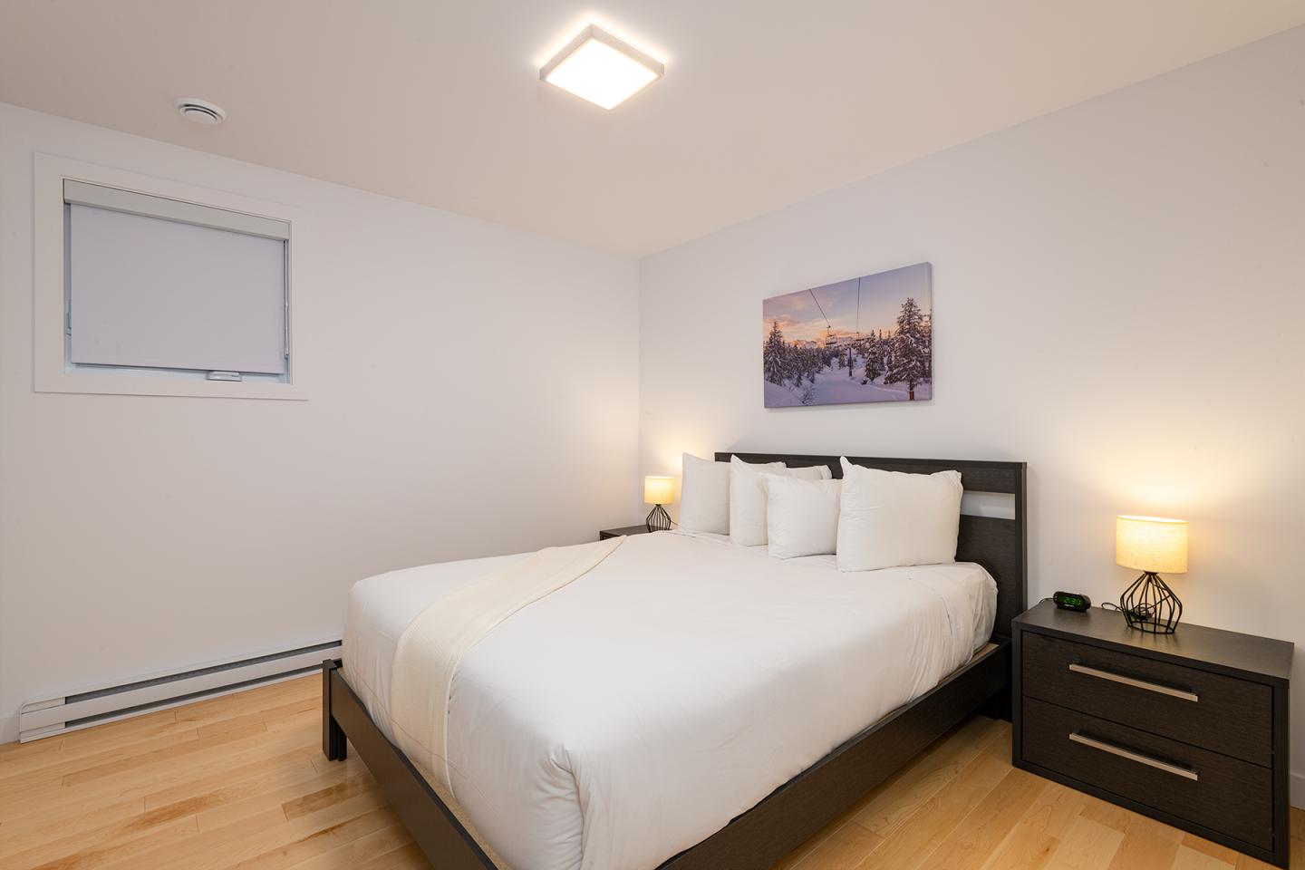 Chambre moderne avec un lit double et deux tables de nuit, éclairage doux.