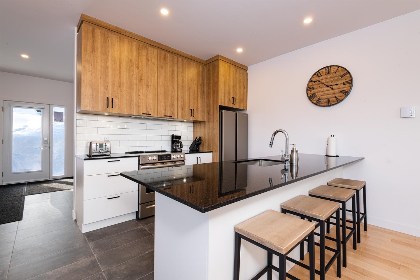 Cuisine moderne avec comptoir en granit et tabourets en bois.