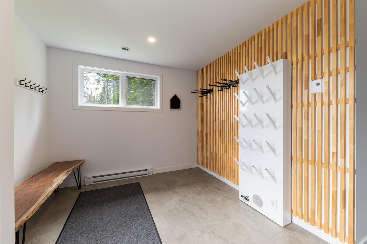 Vestiaire moderne avec banc et crochets, mur en bois et fenêtre.