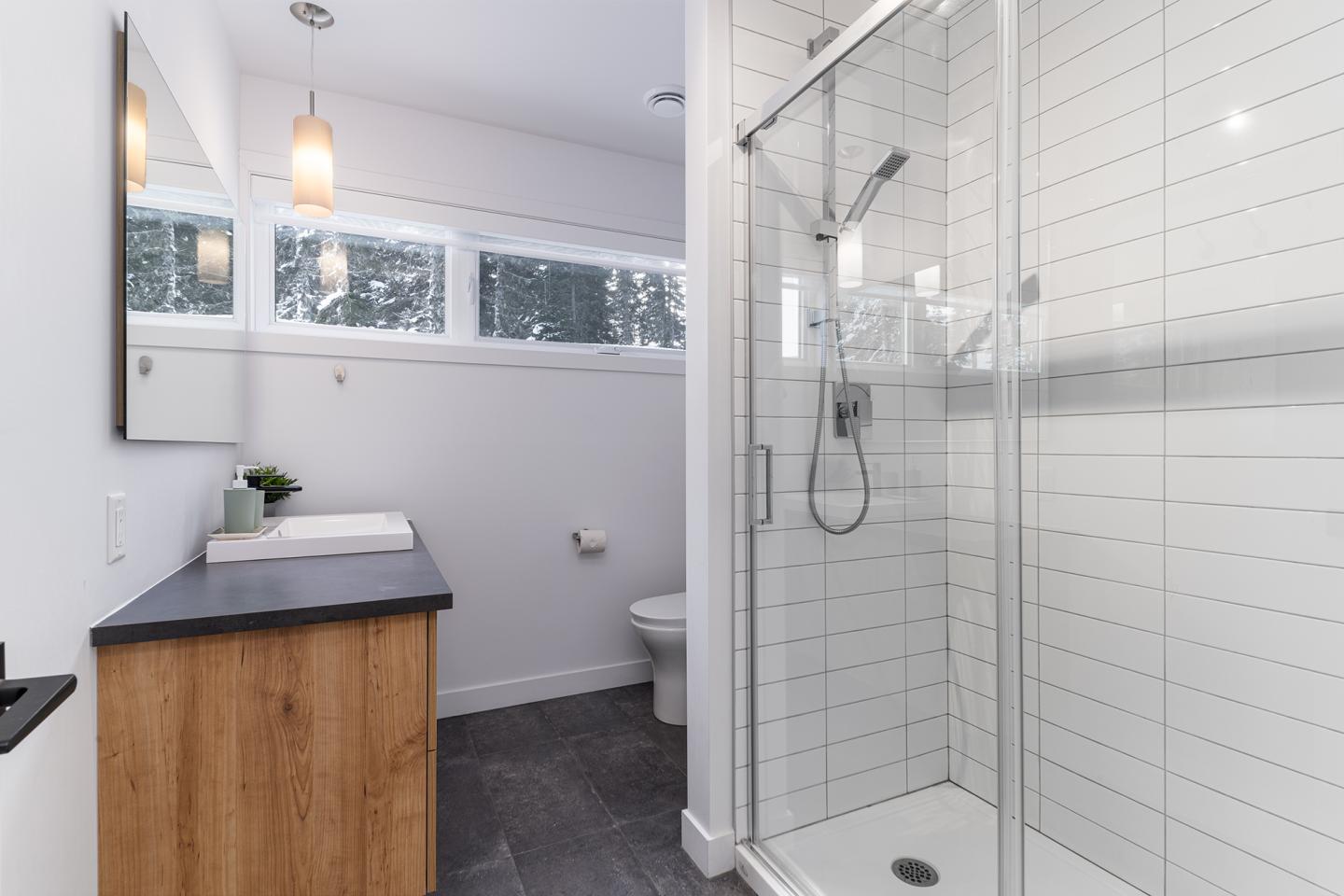 Salle de bain moderne avec douche vitrée et plan de travail en bois.