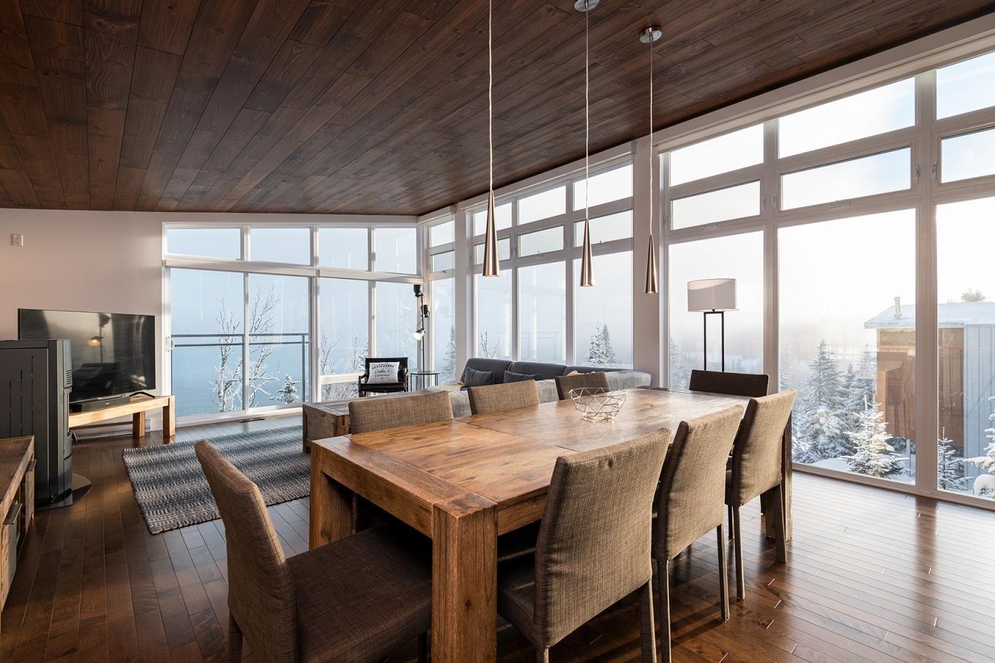 Salle à manger en bois, baignée de lumière, avec vue sur neige.