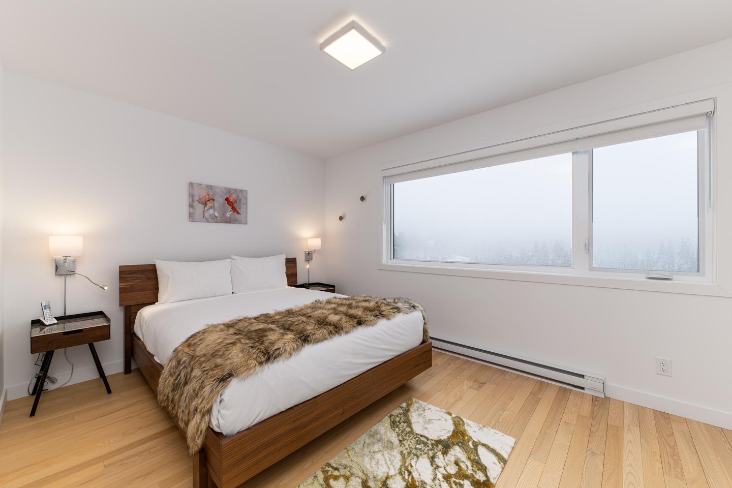 Chambre lumineuse avec lit, couverture en fourrure et grande fenêtre.