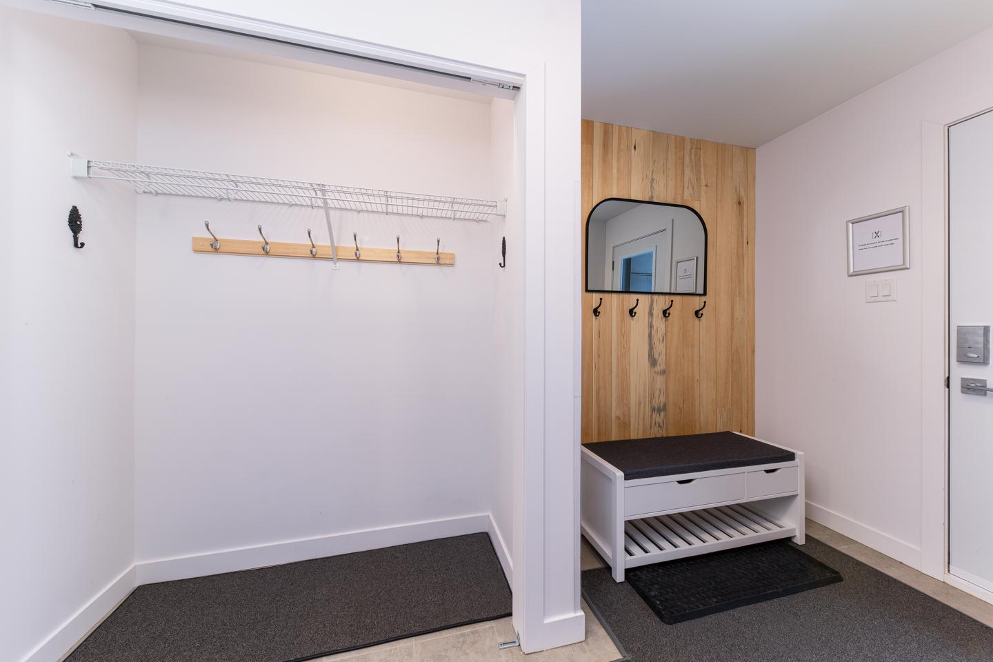 Entrée moderne avec banc de rangement et patères sur mur en bois.