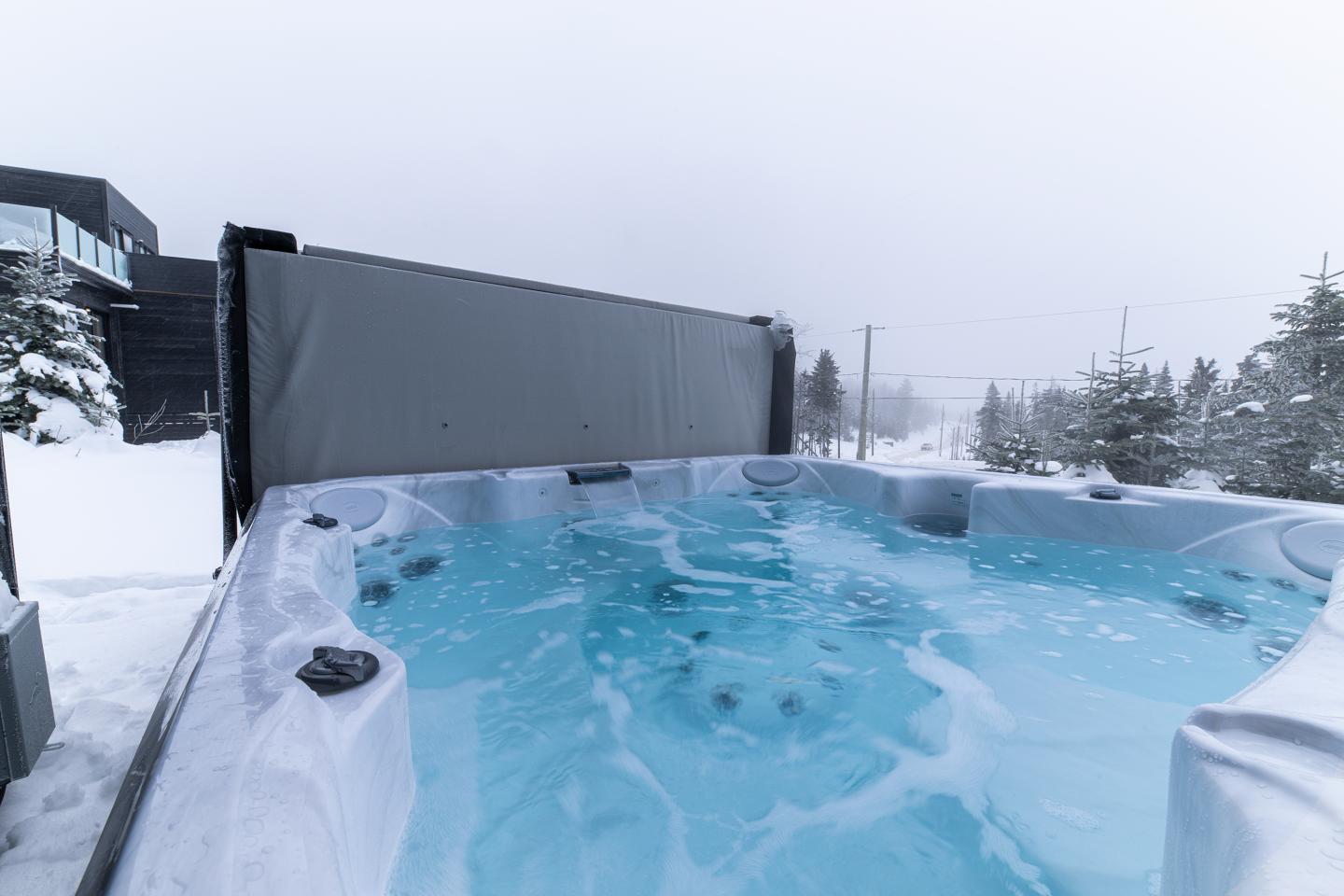 Spa extérieur fumant dans un paysage enneigé.