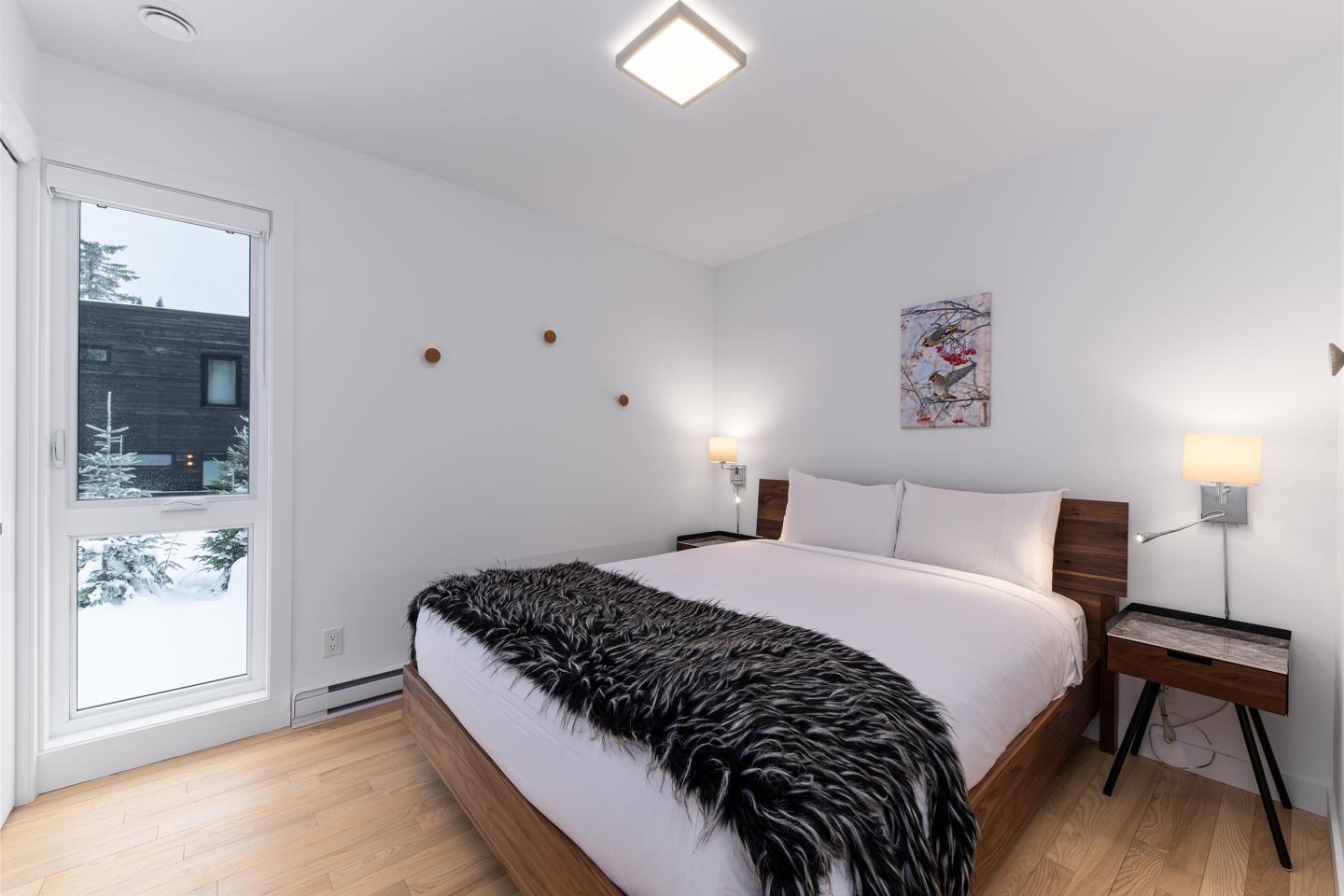 Chambre moderne avec lit double et couvre-lit noir, murs blancs.