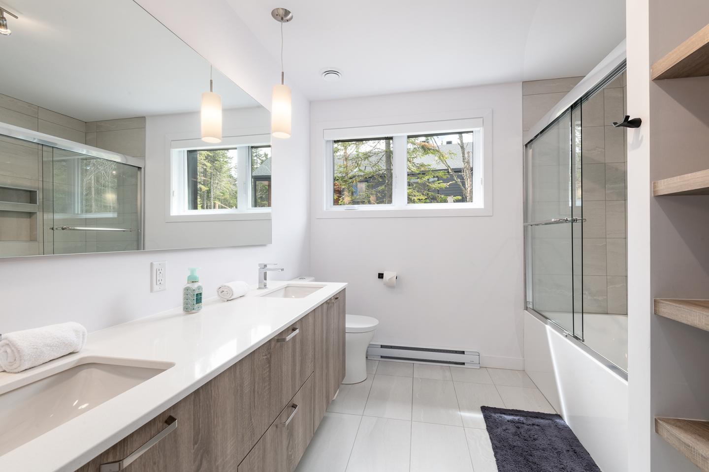 Salle de bain moderne avec douche vitrée et plancher blanc.
