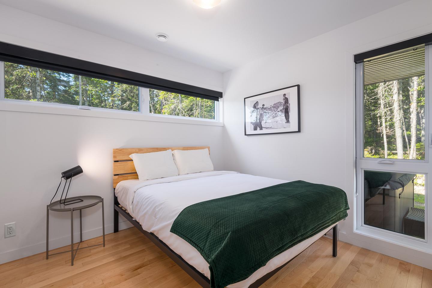 Chambre lumineuse avec lit double, couvre-lit vert, et vue sur jardin.