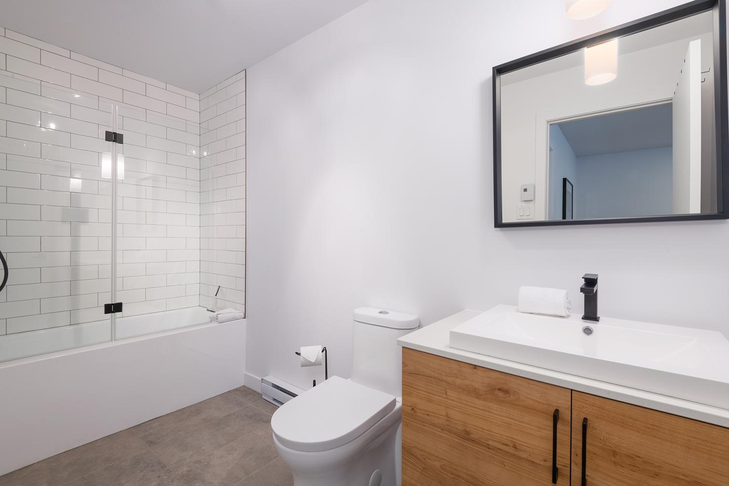 Salle de bain moderne avec baignoire, toilettes, et lavabo en bois.