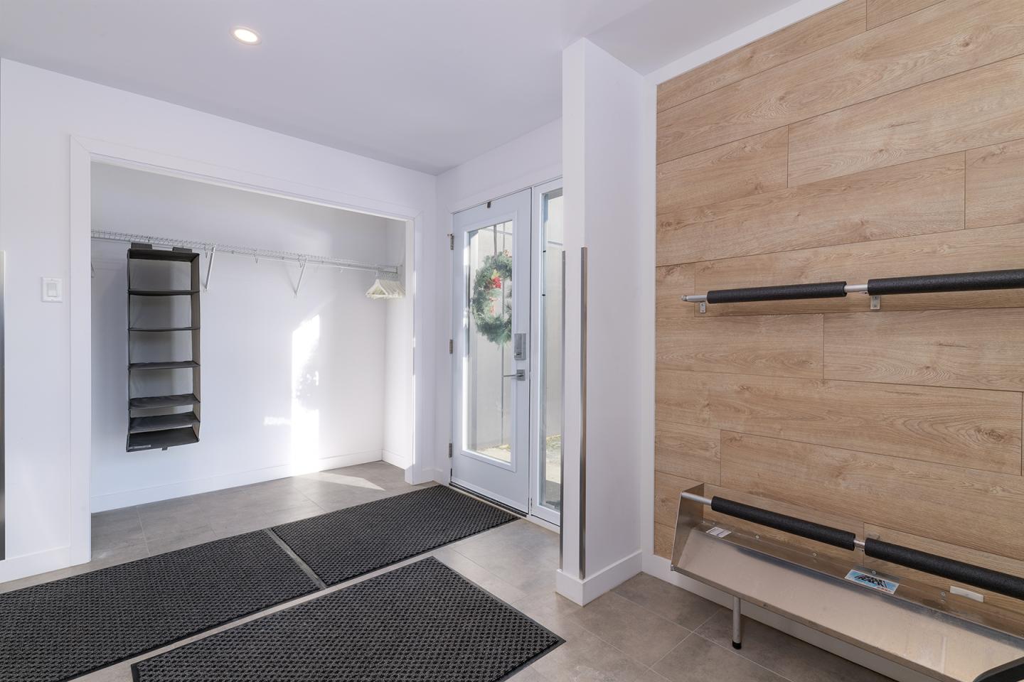 Entrée moderne avec porte vitrée, murs blancs et étagères en bois.