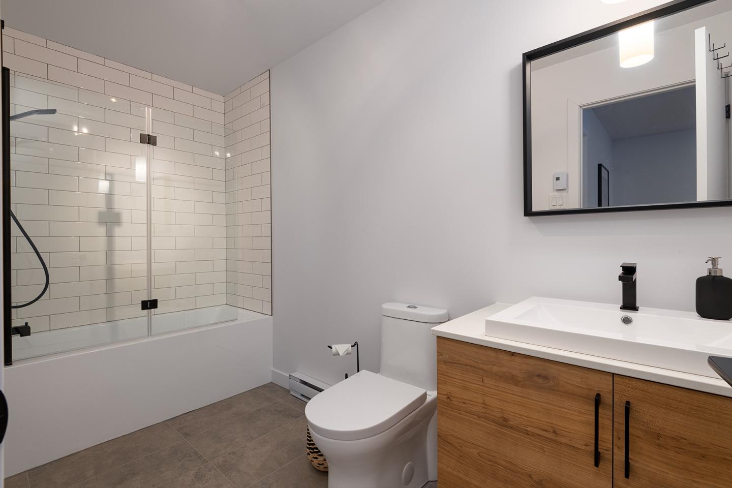 Salle de bains moderne avec baignoire, lavabo et miroir.