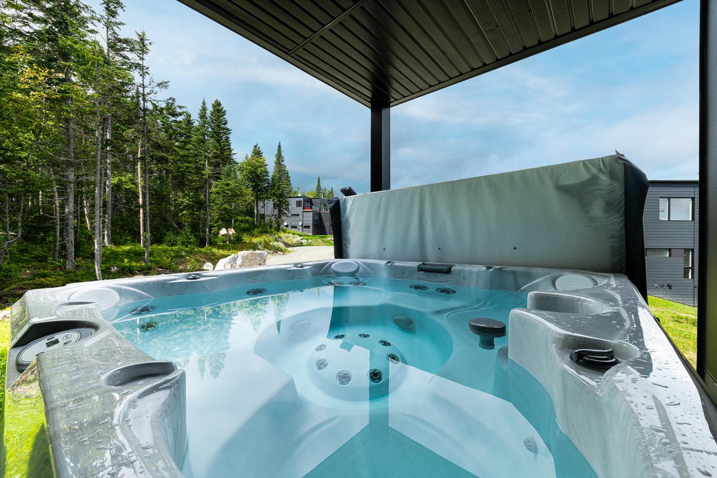 Spa extérieur sur une terrasse, entouré d'arbres et de bâtiments modernes.