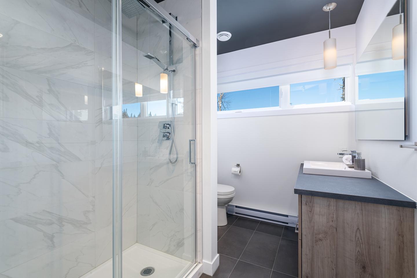 Salle de bain moderne avec douche vitrée, lavabo et WC.