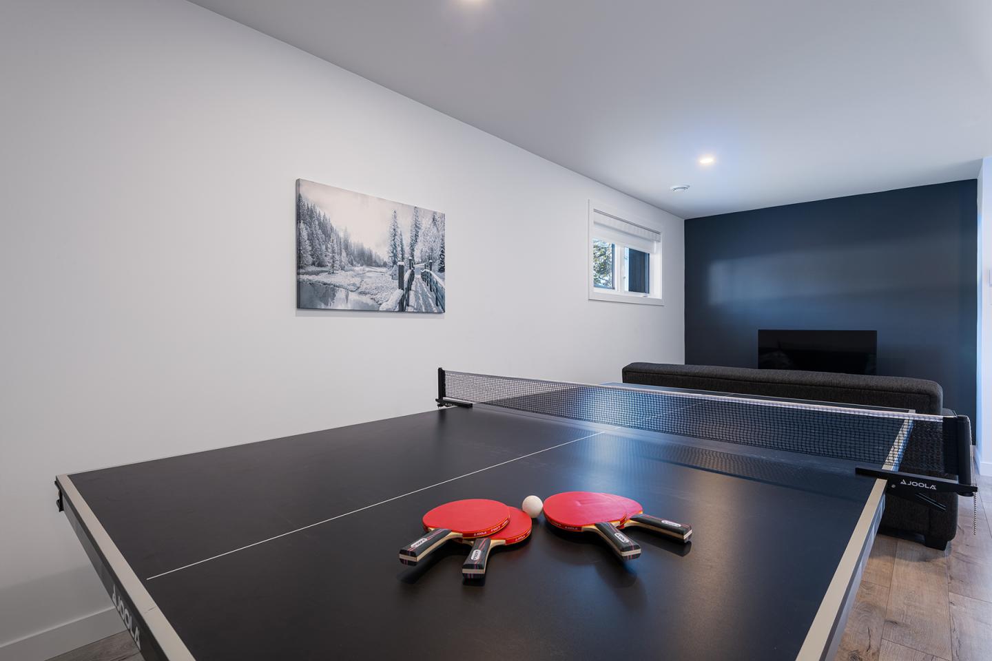 Table de ping-pong avec deux raquettes rouges dans une salle moderne.