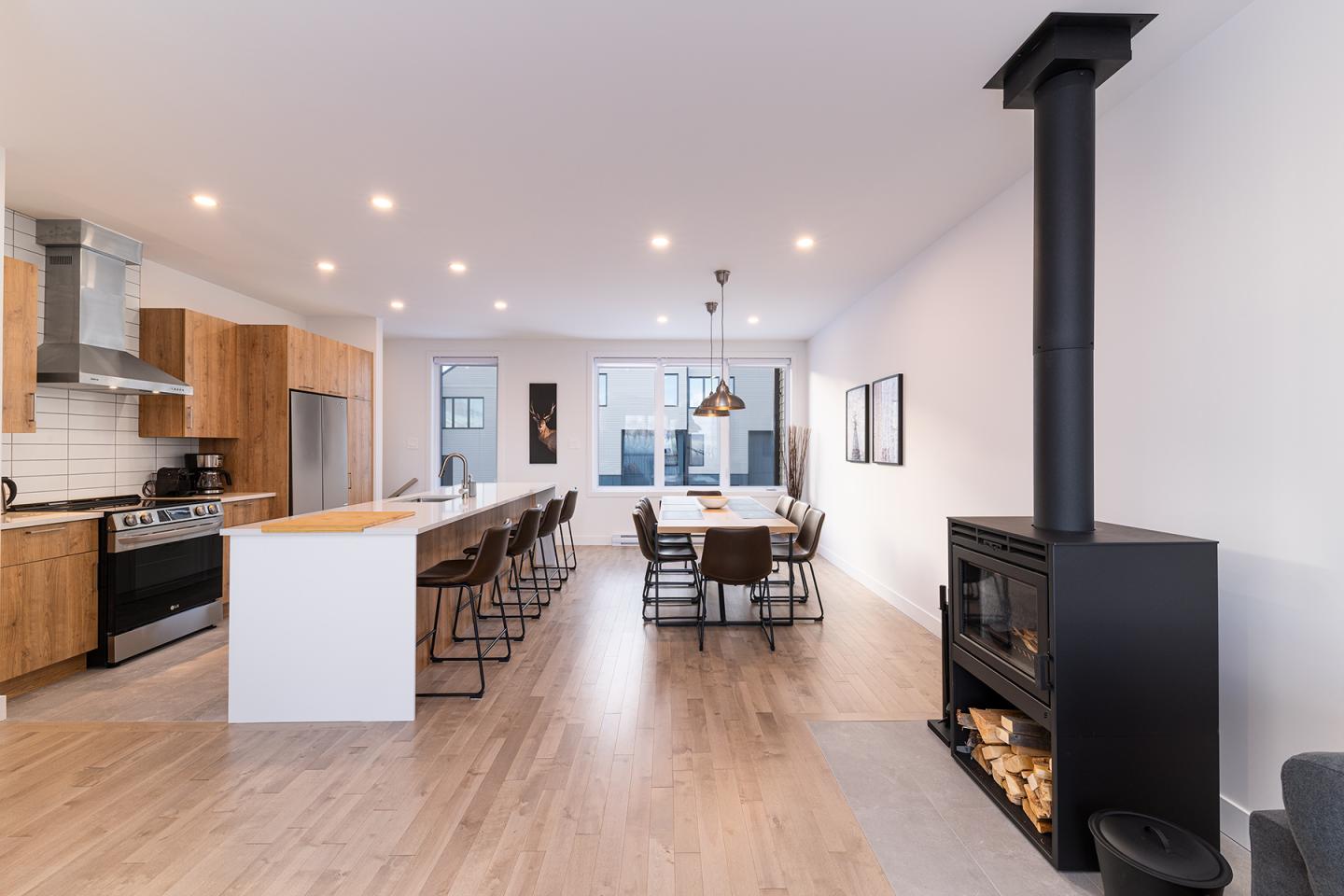 Cuisine moderne avec cheminée, îlot central et table à manger.