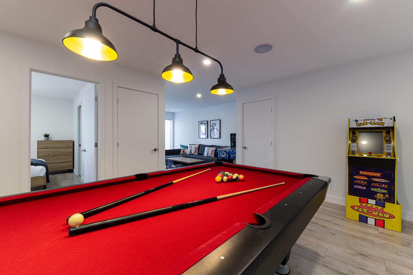 Salle de jeux avec table de billard rouge, fléchettes et jeux d'arcade.