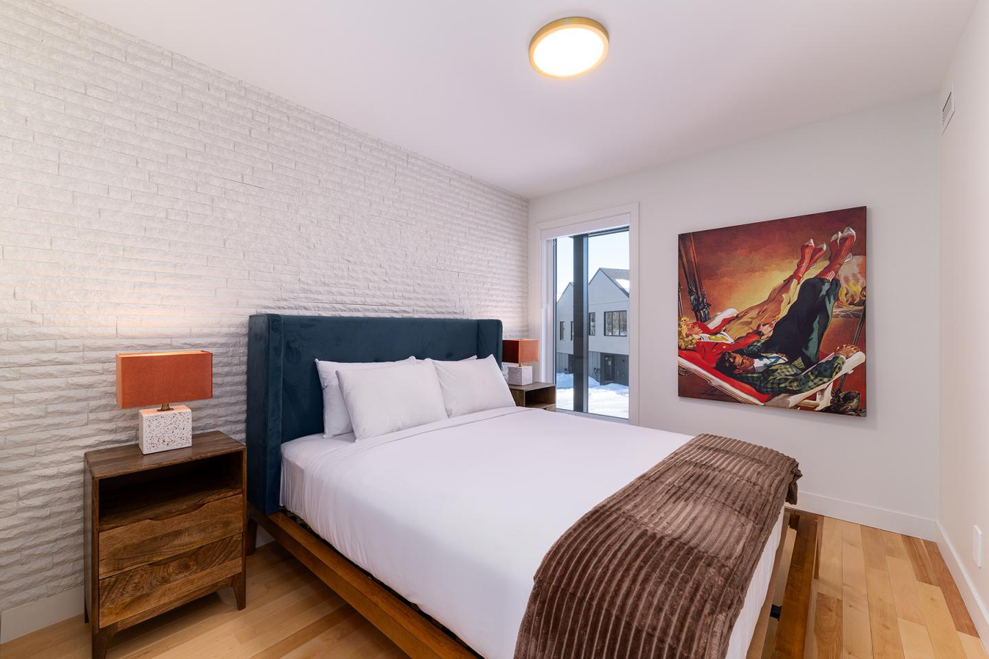 Chambre moderne avec lit double, tableau coloré et lampe de chevet.