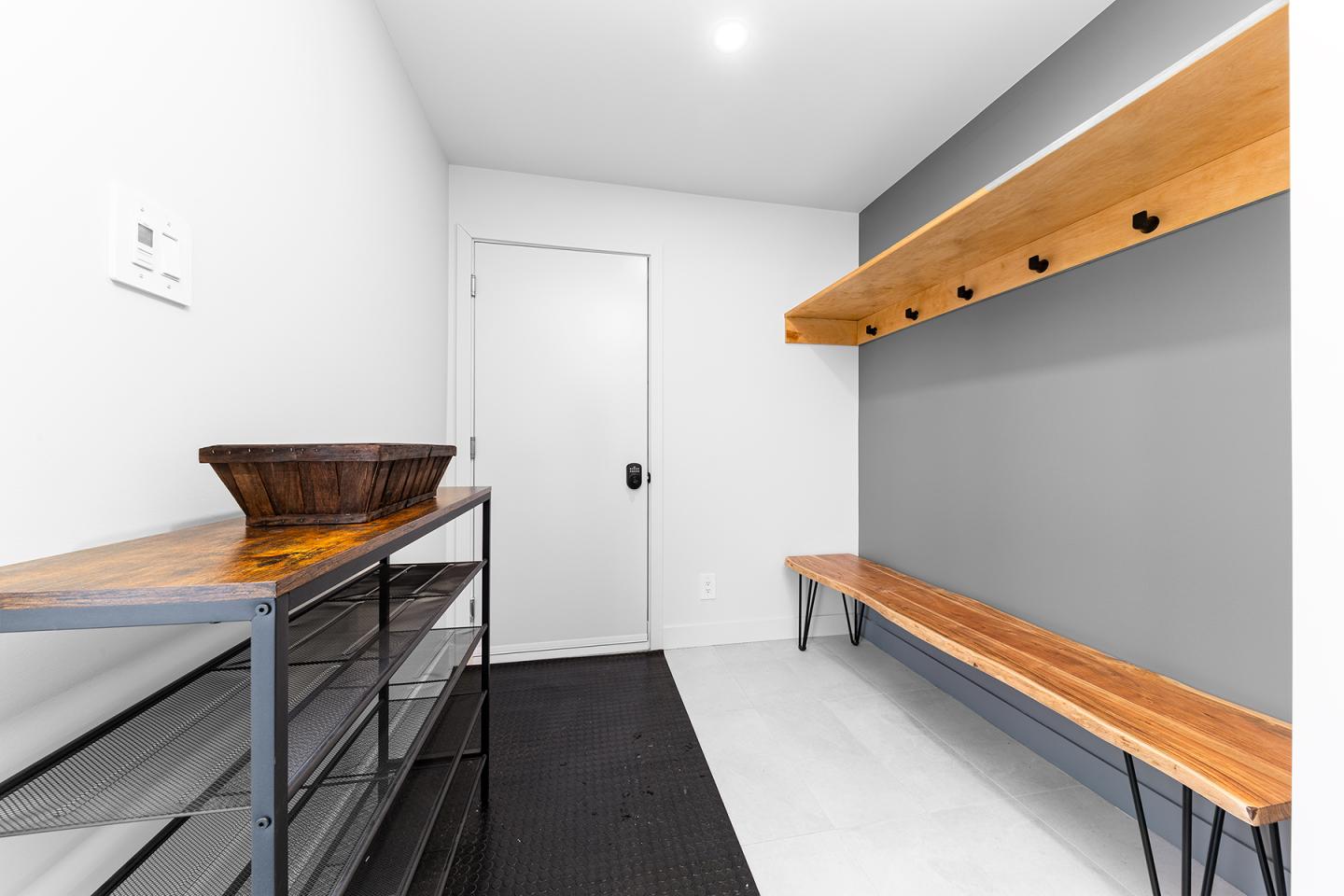 Vestiaire moderne avec bancs en bois, étagères et crochets muraux.