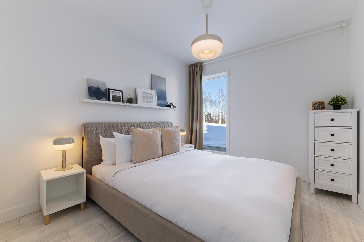 Chambre moderne, lit double, déco sobre, fenêtre avec vue sur l'extérieur lumineux.