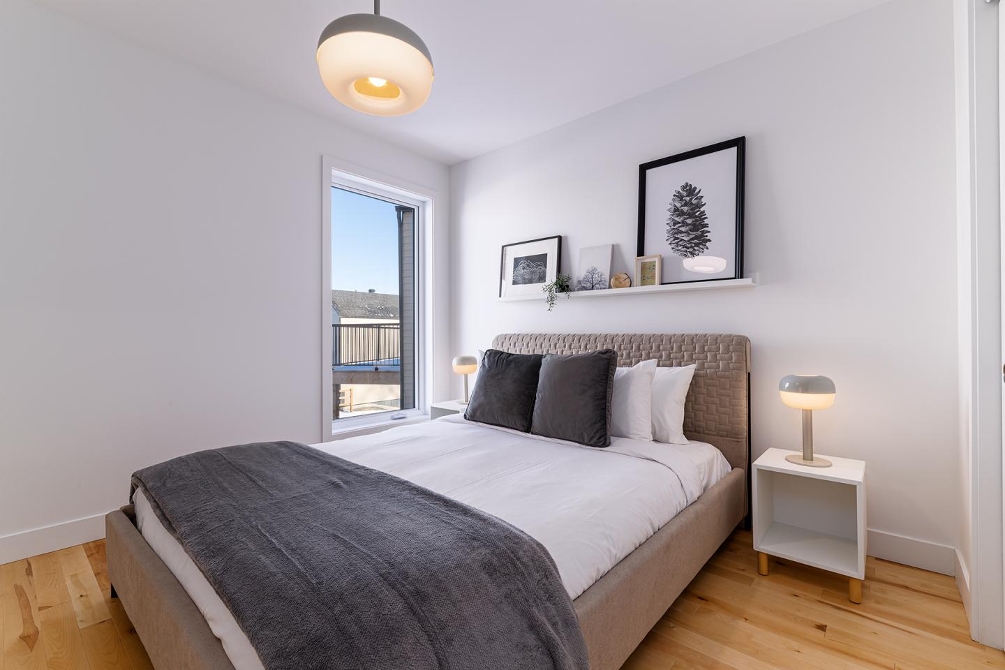 Chambre moderne avec lit double, lampes de chevet et cadres au mur.