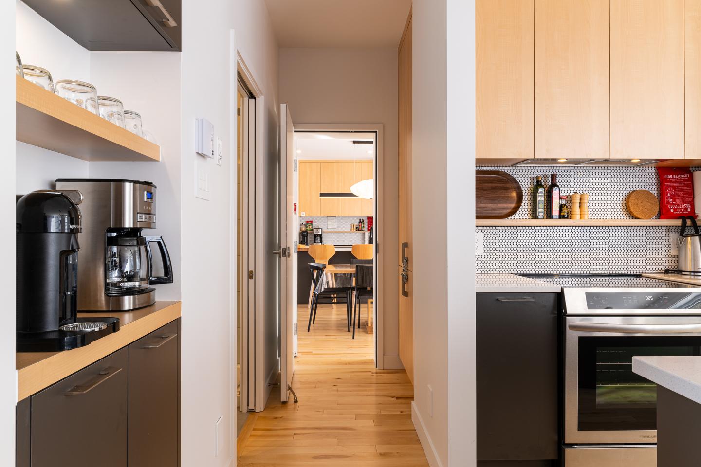 Cuisine moderne avec appareils en acier inoxydable, plancher en bois clair.