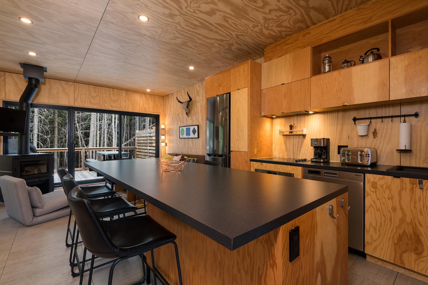 Cuisine moderne en bois avec un grand îlot et des chaises noires.