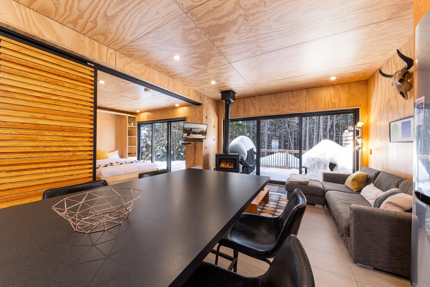 Intérieur chalet moderne, bois clair, grandes baies vitrées, coin salon.